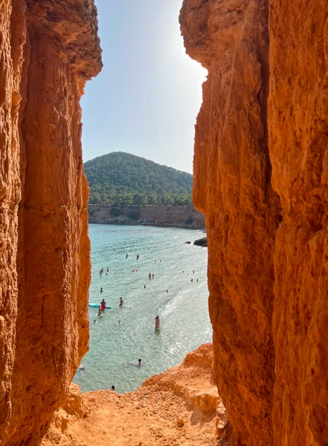 Swimmers in a cove framed by orange cliffs
